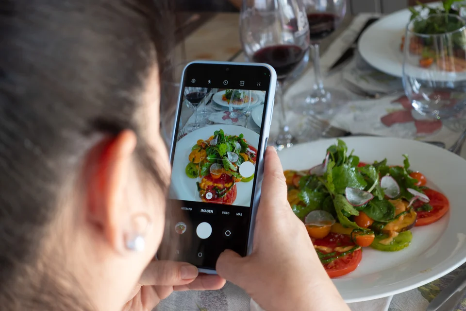 Viajera fotografía un plato durante una experiencia gastronómica