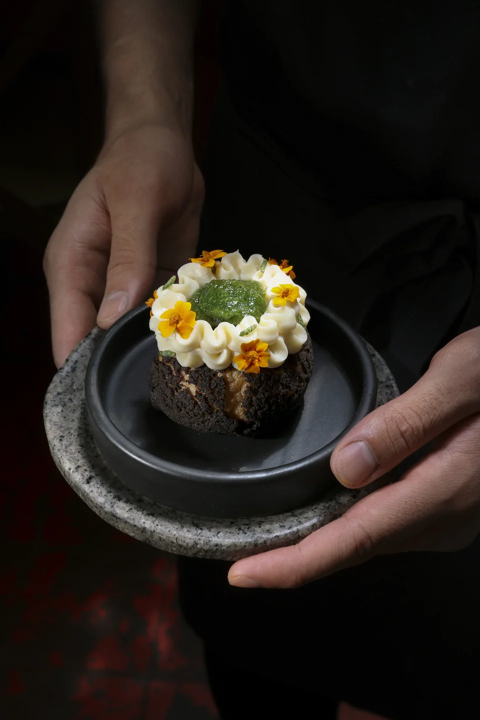 Plato de gastronomía de autor servido entre las manos